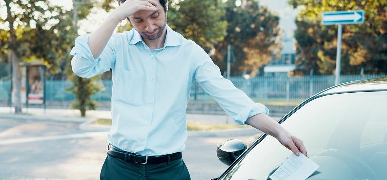 Homme déçu qui trouve un PV sur le pare-brise de sa voiture
