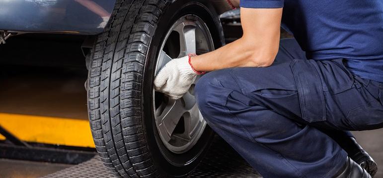 Mécanicien en train de vérifier l’état d’un pneu de voiture